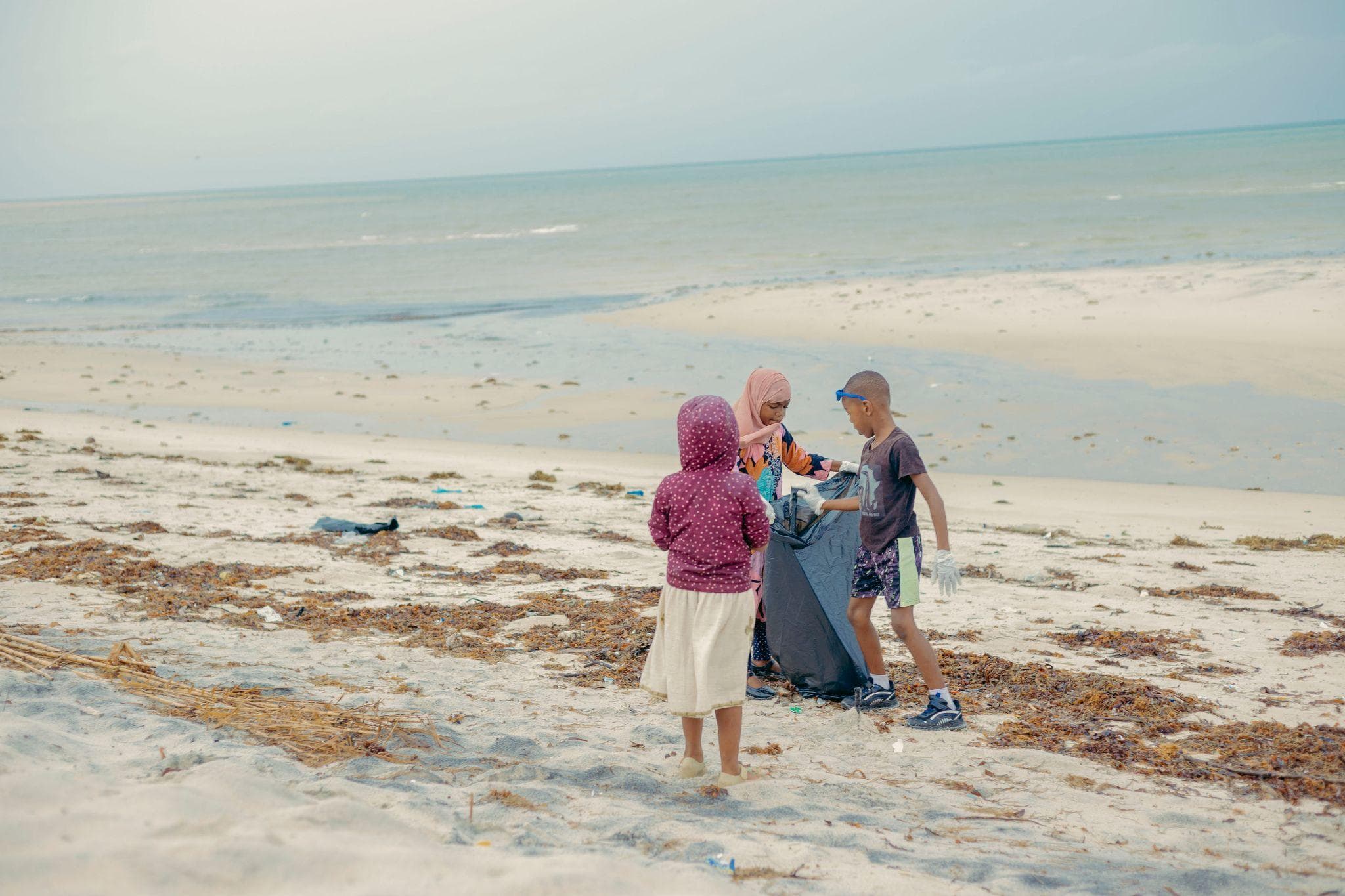 Young participants helping collect litter beside the ocean.