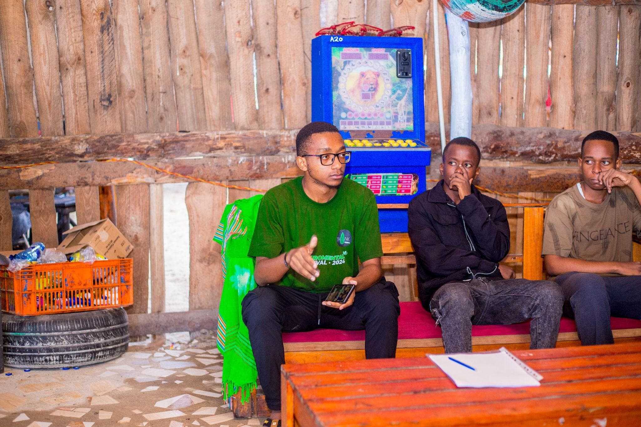 A participant in a green shirt speaking to the seated group.